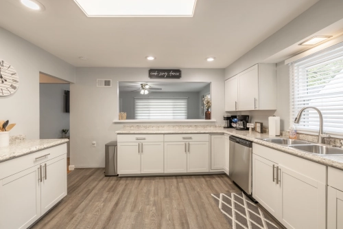 A brightly-lit kitchen, with faux granite countertops and updated, stainless steel appliances.